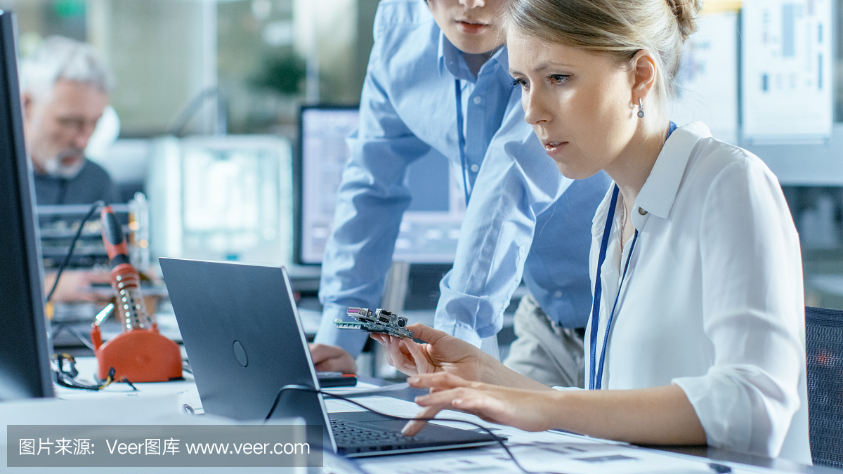 女計算機(jī)科學(xué)家將電路板連接到她的筆記本電腦并開始編程。她在先進(jìn)技術(shù)實(shí)驗(yàn)室工作。